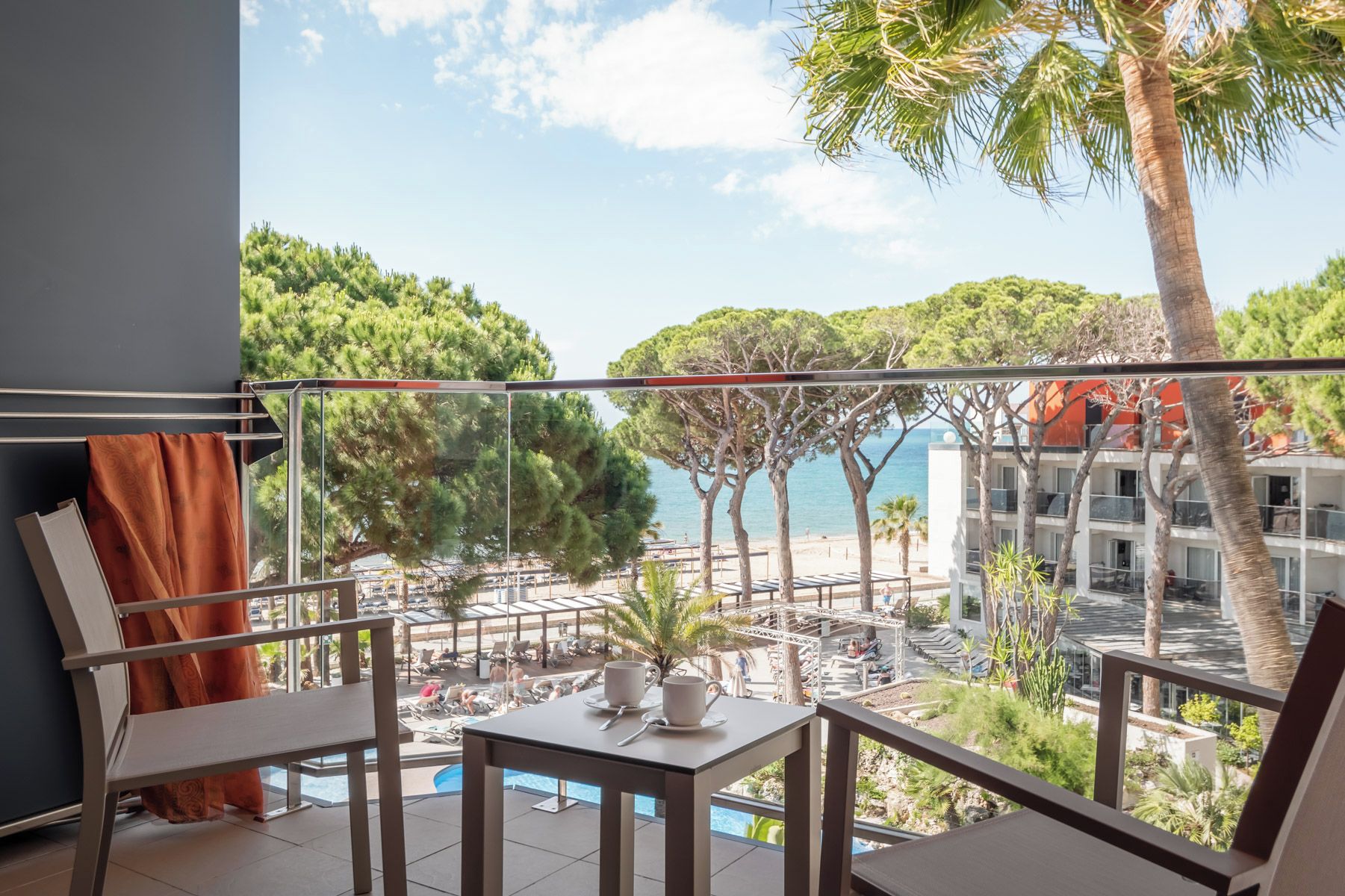Un balcón con piscina, mobiliario exterior y vistas al mar y edificios.