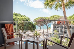 A balcony with a pool, outdoor seating, and a view of the sea and buildings. - Estival Centurión (Cambrils)