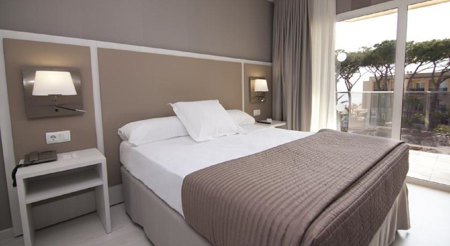 Une chambre d’hôtel avec un lit, des tables de chevet, des lampes et une vue sur l’extérieur.
