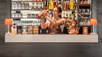 Een bar met een neonbord waarop 'Cocktails' staat, en planken vol met verschillende flessen en glaswerk.