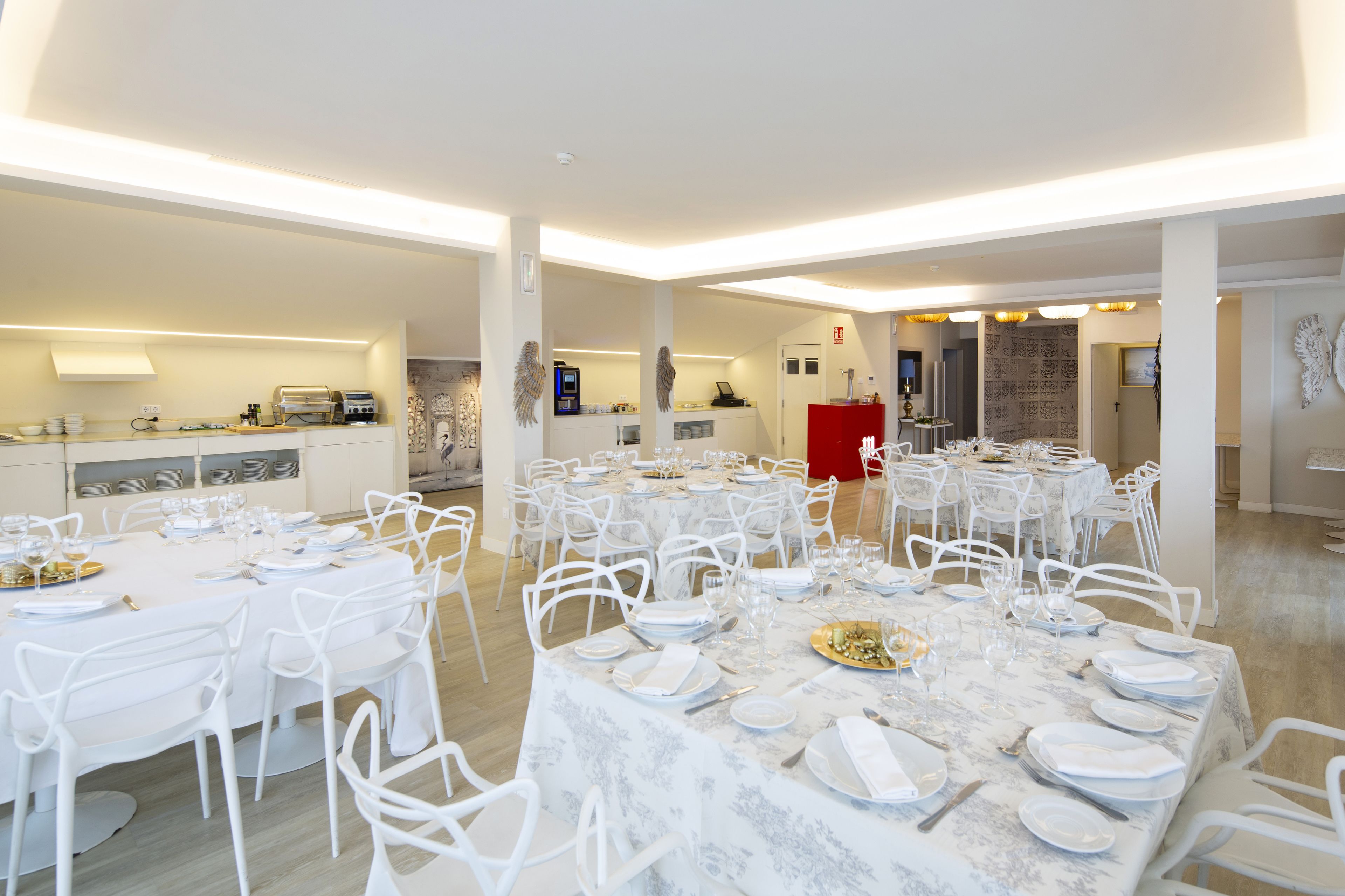 A spacious dining area with multiple round tables set for a meal, surrounded by white chairs.