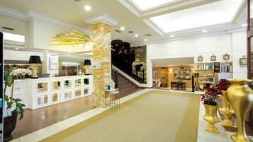 Un hall espacioso con una escalera central, una recepción y una zona de estar.