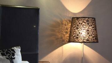 A room with a bed, a patterned lamp, and a wall with a decorative light fixture.
