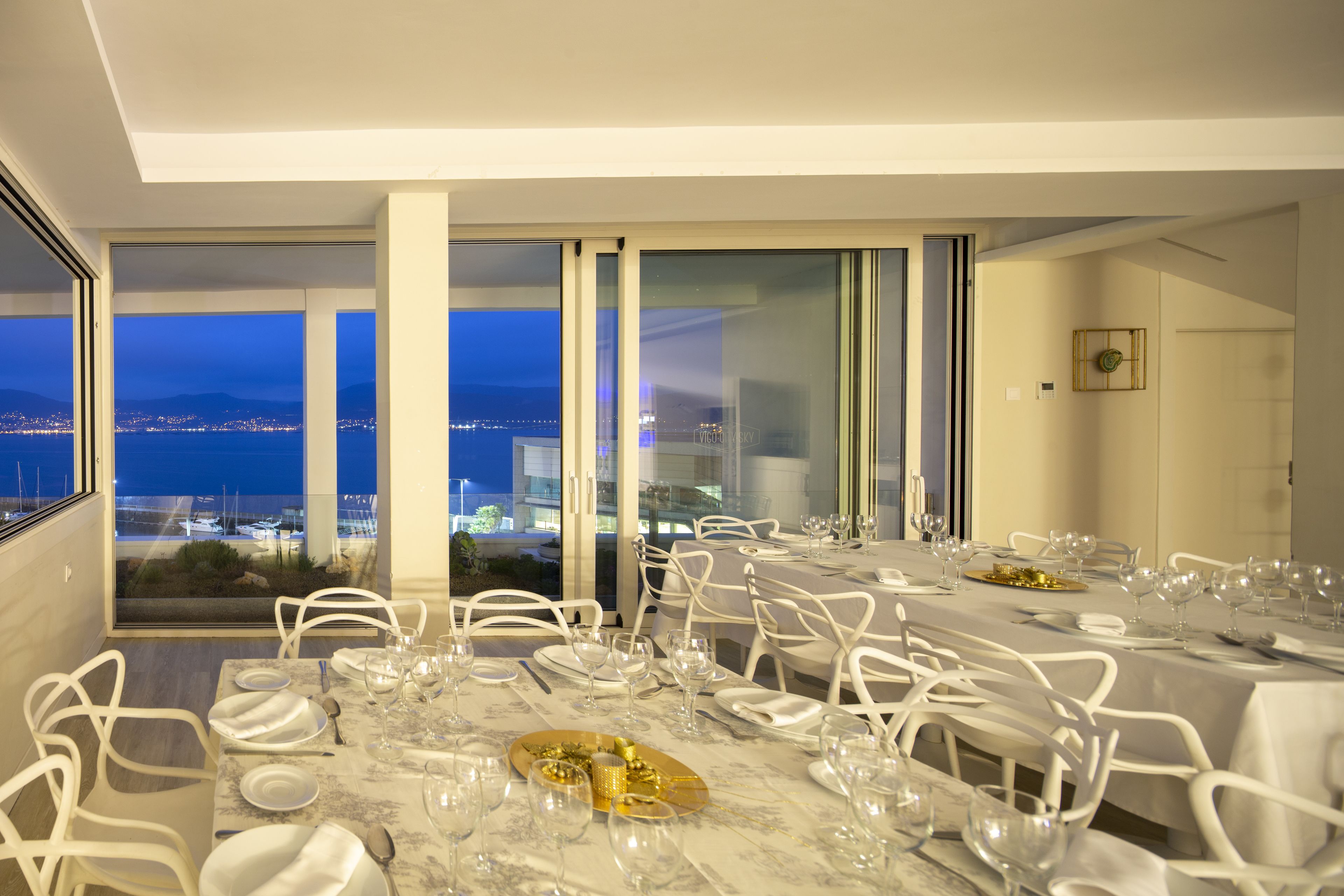 A dining area with tables set for a meal, large windows with a view of the city, and a modern interior design.