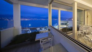 A dining area with a view of a marina and cityscape at dusk. - Hotel Ciudad de Vigo (Vigo)