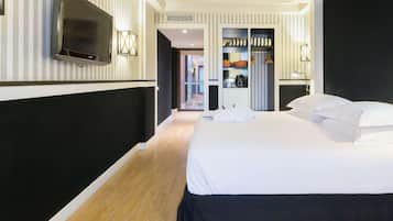 A modern hotel room with a large bed, a flat-screen TV mounted on the wall, a walk-in closet, and a hallway leading to other rooms.