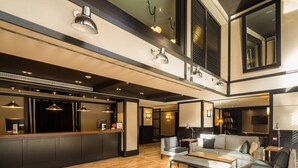 Un moderno vestíbulo de hotel con una recepción, zona de estar y un espejo grande.