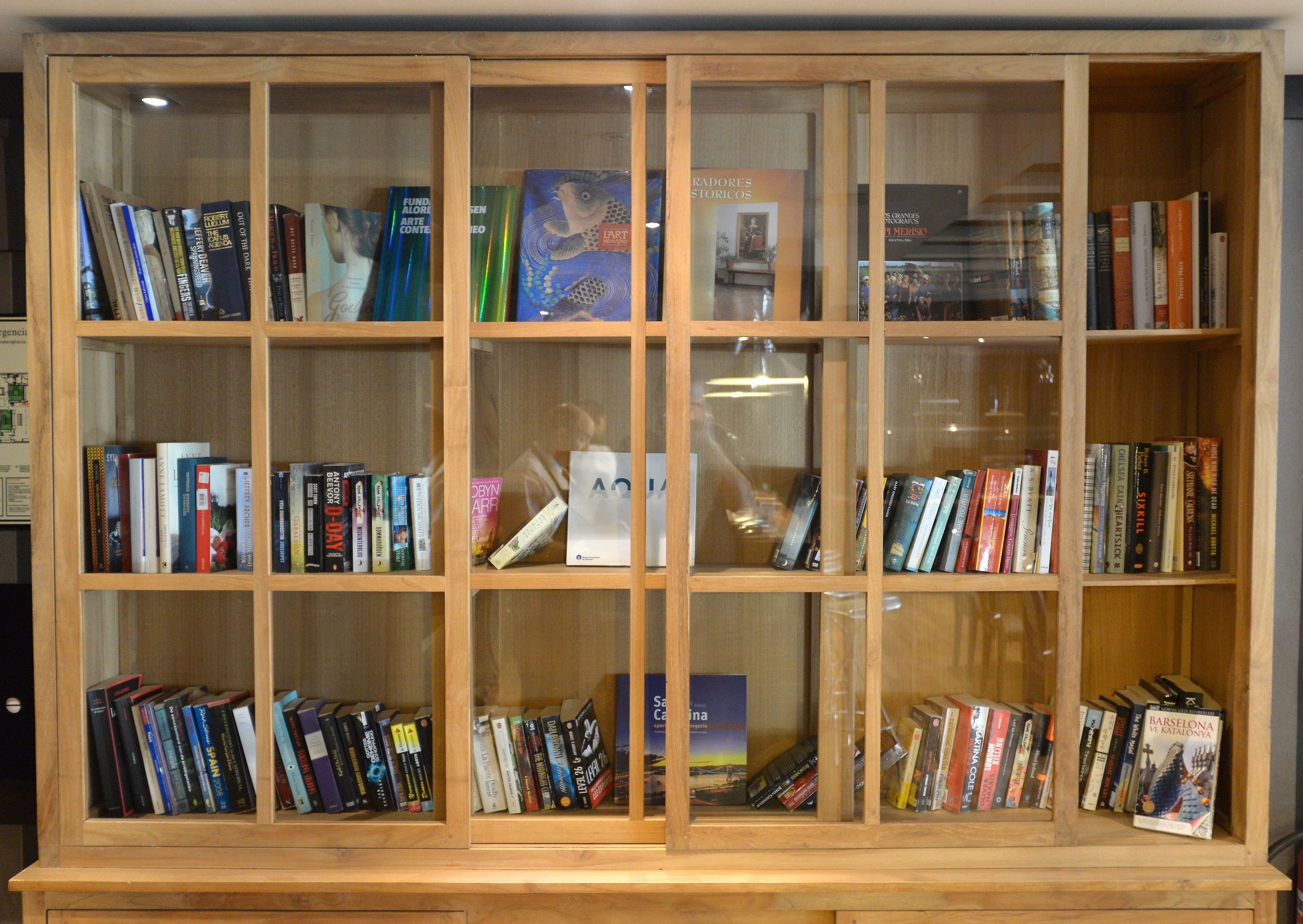Een houten boekenkast met meerdere planken vol boeken.