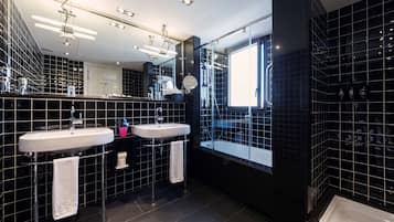 Un baño moderno con dos lavamanos, un espejo grande y una bañera.