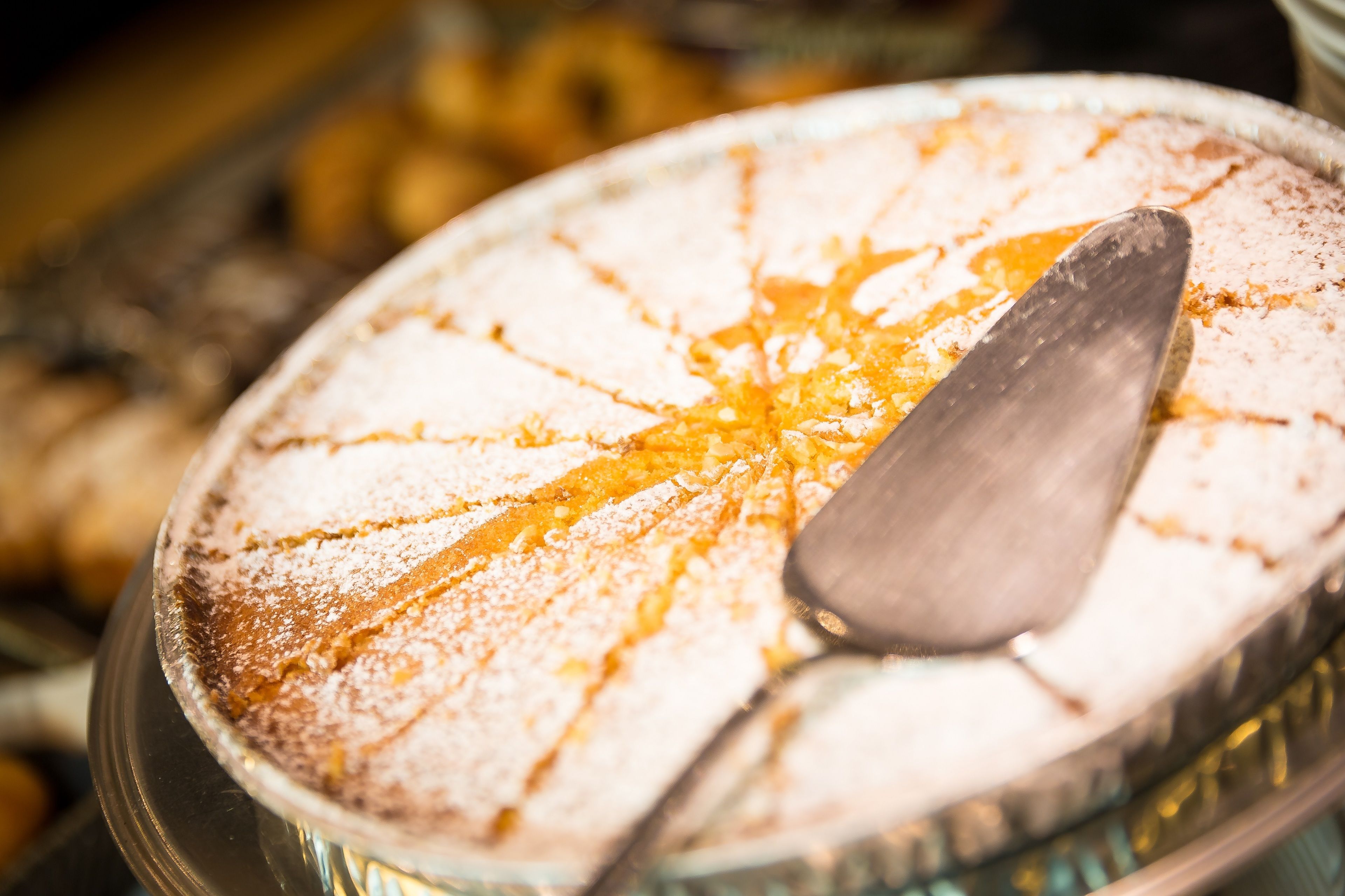 Un dessert rond nappé de sirop doré et saupoudré de sucre glace, servi sur un plateau en métal.