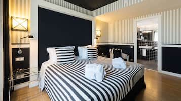 Habitación de hotel con una cama grande, mesitas de noche, un teléfono y un baño visible a través de una puerta abierta.