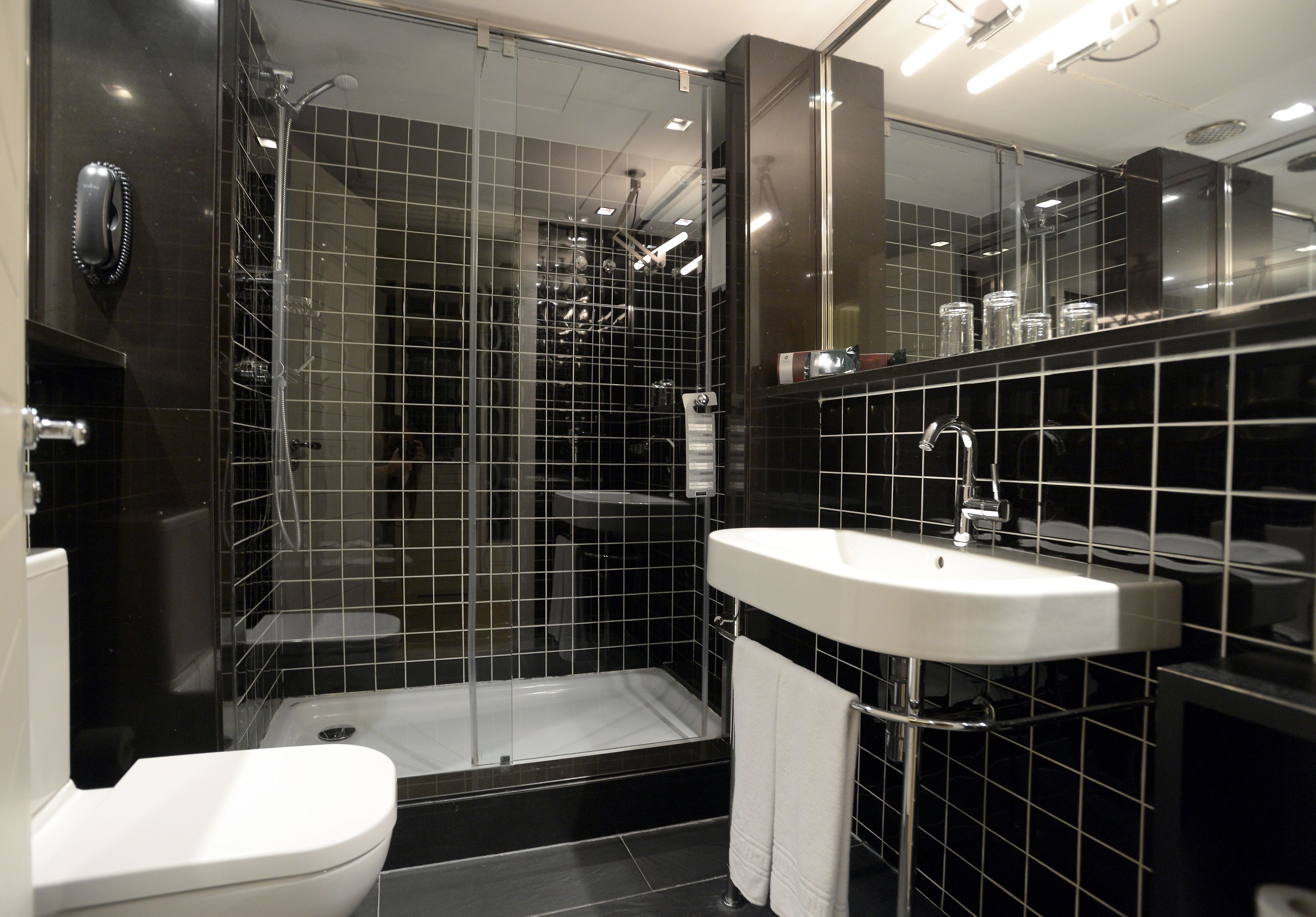 A modern bathroom with a glass-enclosed shower, a white sink, and a toilet.