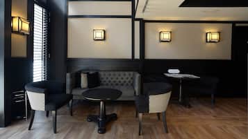 A modern lounge area with a sofa, two armchairs, a coffee table, and a small table with a menu.