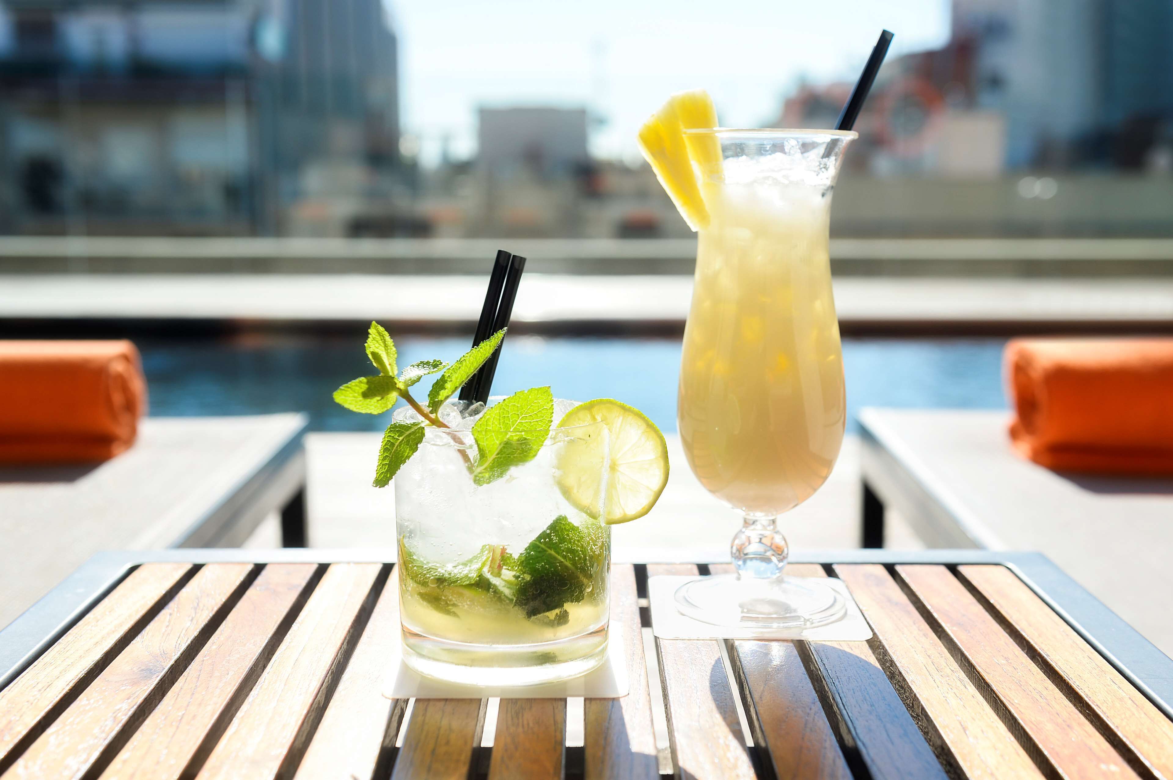 Dos bebidas sobre una mesa de madera, con vista a la ciudad al fondo.