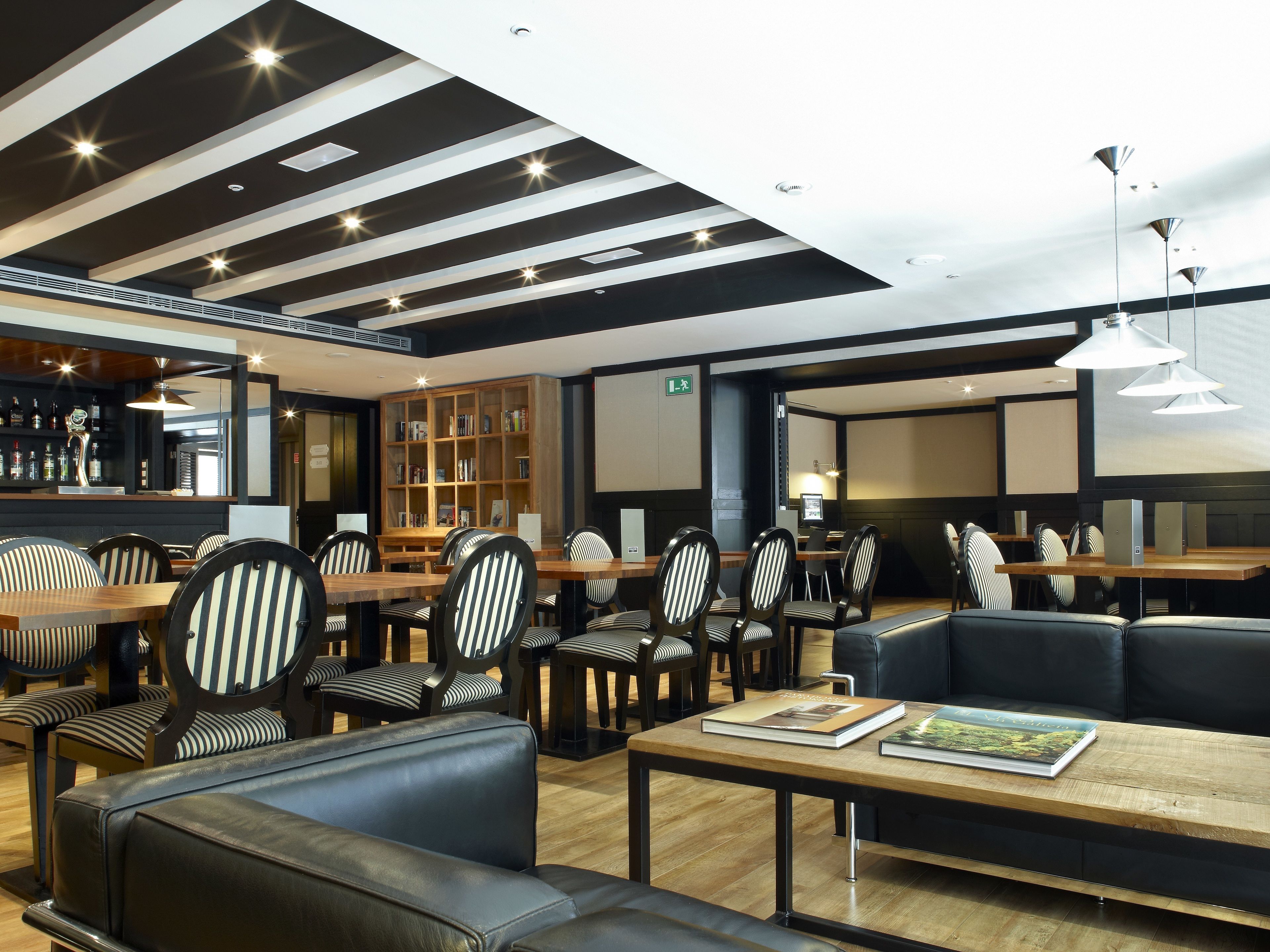 Um restaurante moderno com cadeiras listradas, um bar e uma estante de livros.