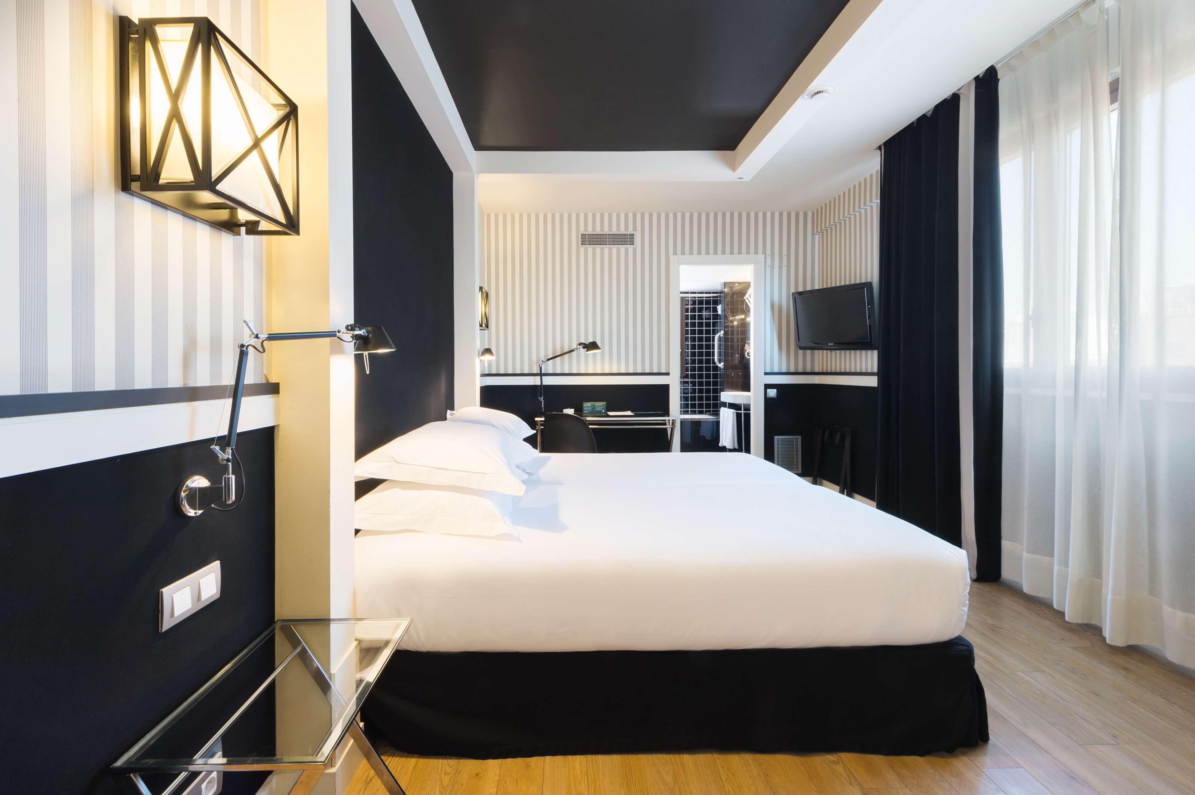 Une chambre d’hôtel moderne dotée d’un grand lit, d’un bureau, d’une télévision et d’une salle de bain avec douche et toilettes.