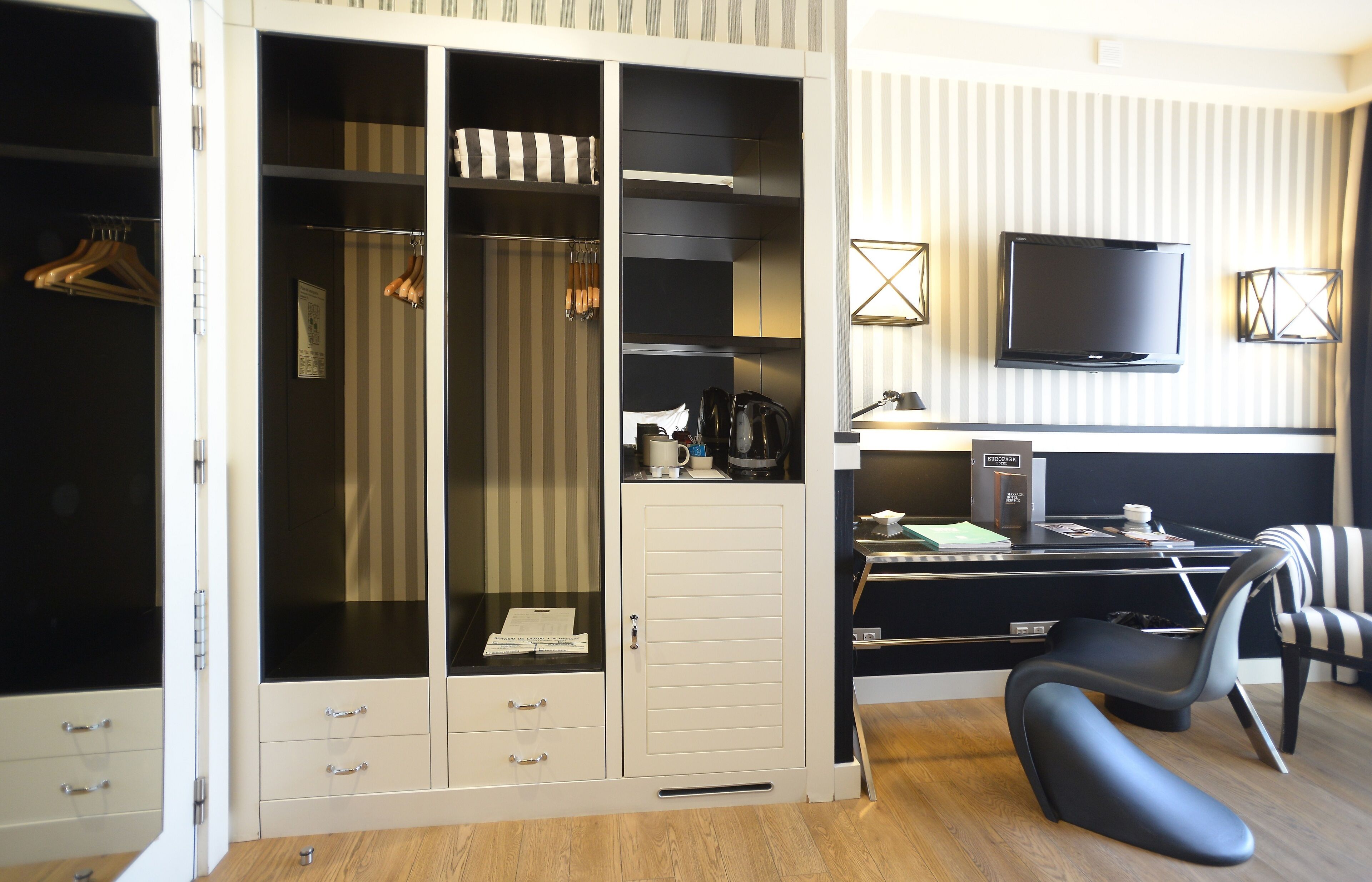 Et hotelværelse med et stort walk-in closet, et skrivebord med computer, en stol og et fjernsyn.
