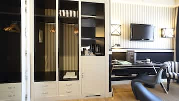 A hotel room with a large walk-in closet, a desk with a computer, a chair, and a television.