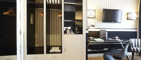 Habitación de hotel con un amplio vestidor, un escritorio con computadora, una silla y un televisor.
