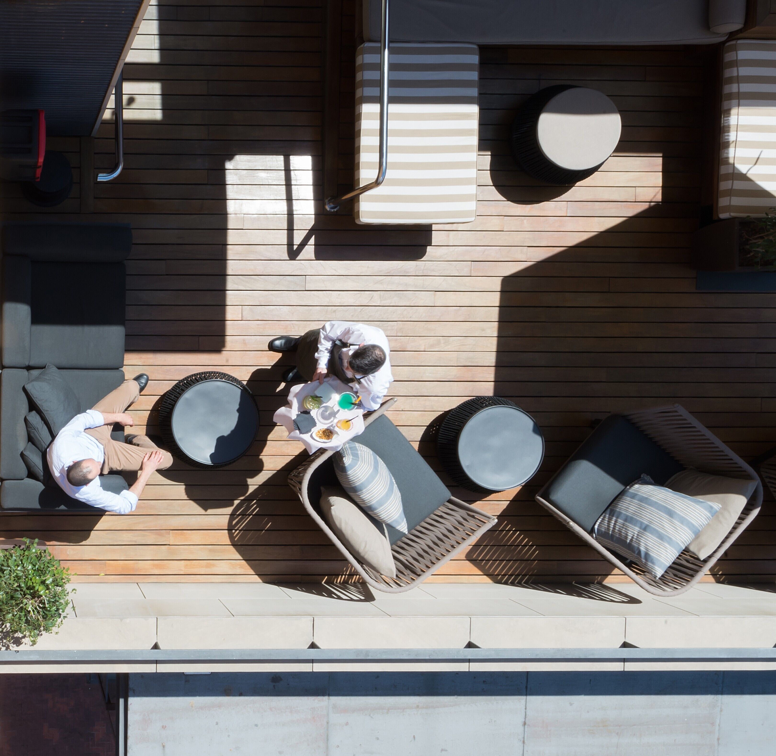 A rooftop terrace with outdoor seating, including a sofa and chairs, and a dining table with a person seated.