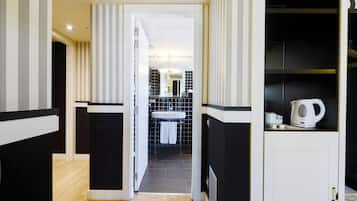 Un baño moderno con una paleta de colores blanco y negro, un lavamanos visible y una tetera sobre la encimera.