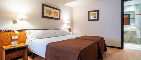 A hotel room with a bed, two bedside tables, a nightstand, and a large window.