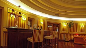 A hotel lobby with a curved ceiling, wooden furniture, and wall-mounted lamps. - Hotel Hoyuela (Santander)