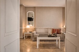 Una habitación con un sofá, una mesa de centro, una mesita auxiliar con lámpara y un espejo.