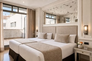 A hotel room with a large bed, a nightstand, a mirror, and a window with curtains. - VP Jardín de Recoletos (Madrid)