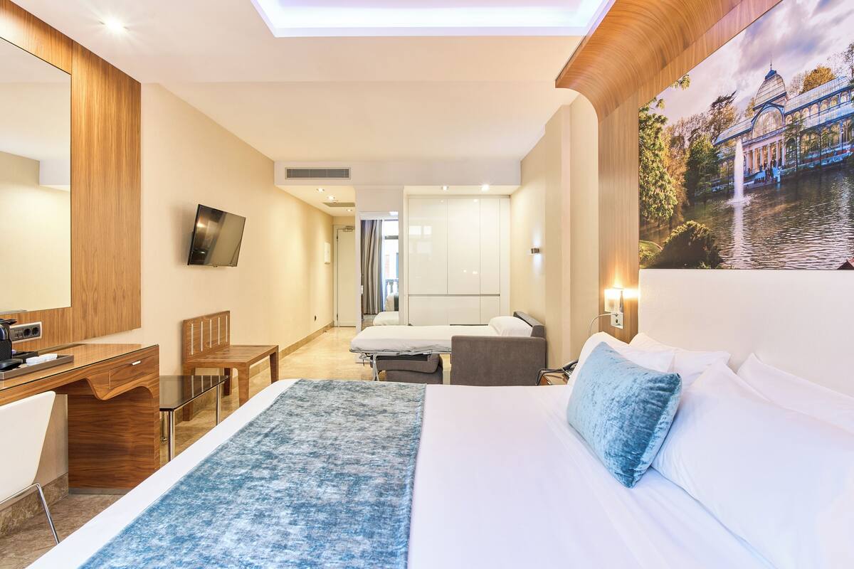 Ein Hotelzimmer mit Bett, Schreibtisch, Stuhl, Fernseher und Bad.