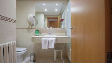 A bathroom with a toilet, sink, mirror, and a trash bin.