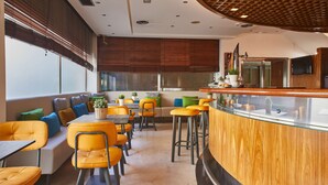 Ein modernes Restaurant mit Barbereich, Sitzgelegenheiten mit orangefarbenen Stühlen und einer Wand als Holzdekor.