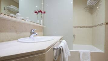 Un baño con lavamanos, espejo y zona de ducha.