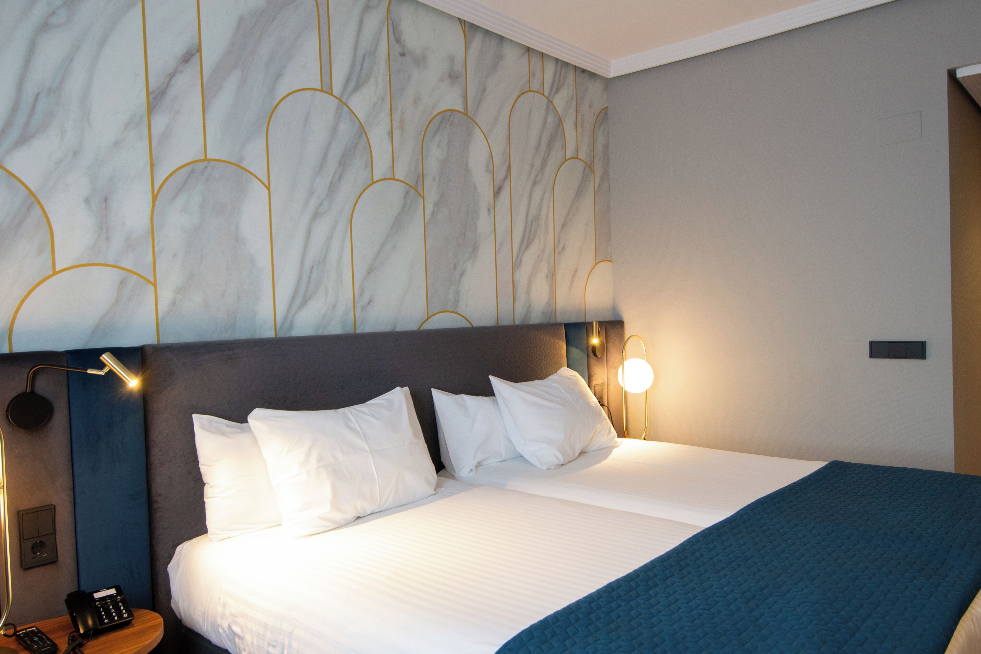 Ein Hotelzimmer mit einem Bett, einem Nachttisch mit Telefon und einer Wandleuchte.