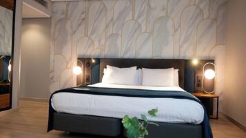 A modern bedroom with a large bed, two bedside tables with lamps, and a marble-patterned wall.