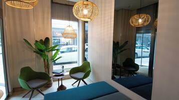 A modern interior with green chairs, a blue bench, and wicker pendant lights.