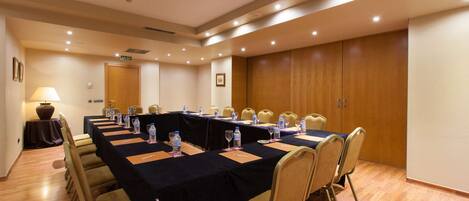 A conference room with a long table, chairs, water bottles, and a lamp.