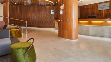 A hotel reception area with a wooden wall, a reception desk, and a sign indicating Wi-Fi availability.