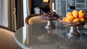 A dining table with two glass stands, one with cherries and the other with oranges.