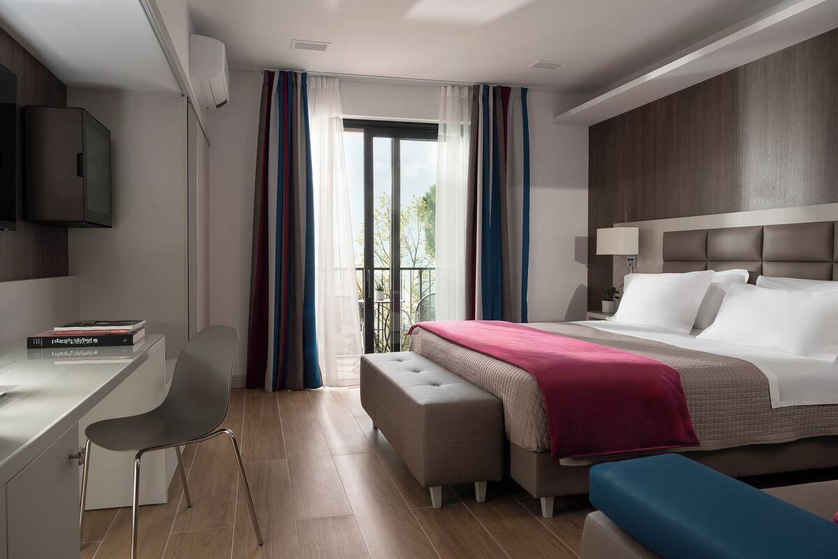 A modern hotel room with a bed, a desk, and a chair.