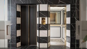 An elevator with a black and white marble design, a digital display, and a mirrored wall.