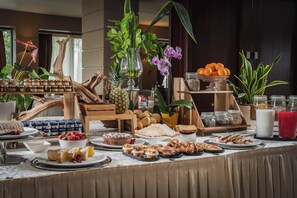 Une table de buffet proposant une variété d’aliments, notamment des pâtisseries, des fruits et des condiments.