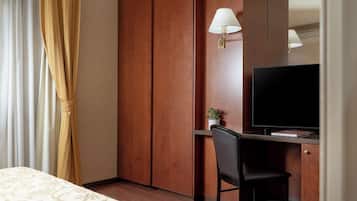 Une chambre d’hôtel comprenant un lit, un bureau avec une chaise, une télévision et une armoire.
