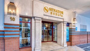 El exterior del hotel Senator Huelva con una entrada destacada, número 10, y un área adoquinada.