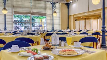 A dining area with tables set for breakfast, featuring a variety of food items and a menu sign.