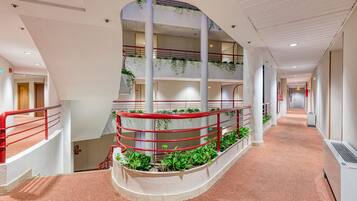A multi-level interior with a central staircase, railings, and greenery.