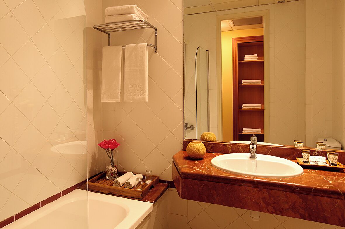 A bathroom with a bathtub, a sink, a mirror, and a towel rack.