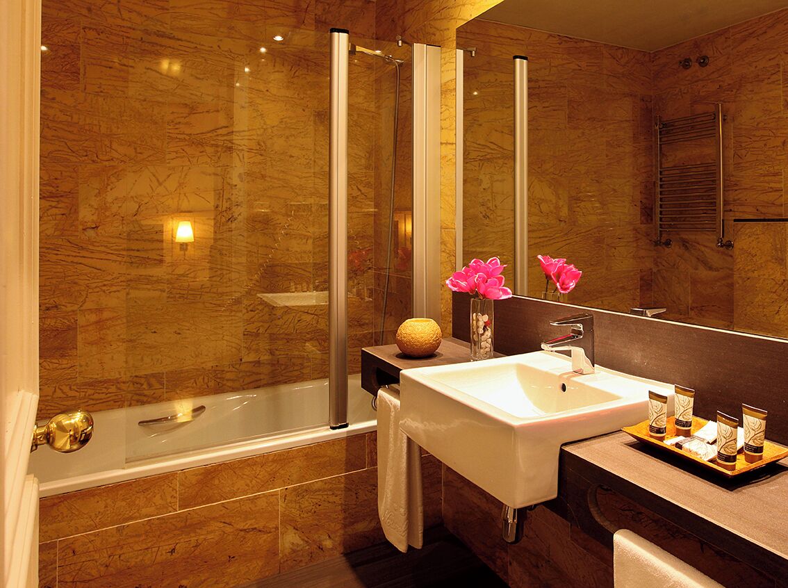 Un baño moderno con bañera, un espejo grande, lavabo y tocador con adornos.