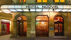 The exterior of the HOTEL NOUVEL with a classic facade, large arched entrance, and illuminated signage. - Hotel Nouvel (Barcelona)