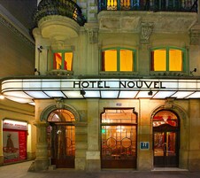 Exterior do HOTEL NOUVEL, com fachada clássica, grande entrada em arco e sinalização iluminada.